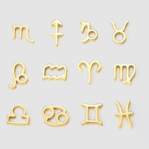 Set of twelve gold zodiac signs stainless steel pendants arranged on a gray background