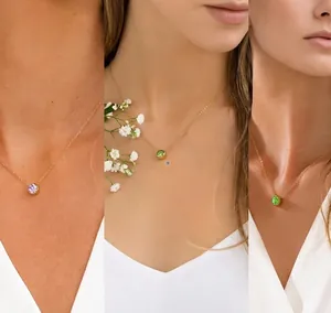Detail showing minimalist round purple and green gemstone pendants on thin gold chains