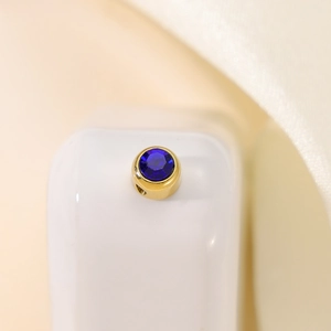 Macro shot of a round gold stainless steel pendant with a faceted deep blue gemstone