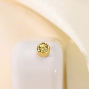 Macro shot of gold circular pendant charm with a bezel-set pale yellow faceted crystal