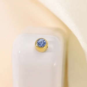 Macro shot of gold cylinder charm with sky blue zircon inlay for DIY jewelry