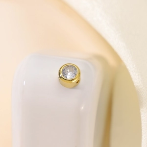 Macro shot of gold-plated round charm with brilliant-cut cubic zirconia inlay