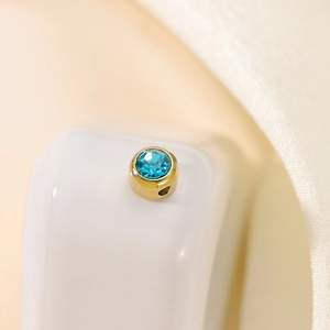 Detailed macro shot of a gold round charm with an inlaid blue zircon for DIY jewelry