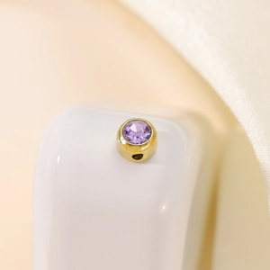 Macro view of gold slider bead with purple faceted crystal for DIY jewelry making