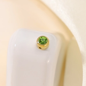 Macro shot of gold circular pendant with green rhinestone for DIY jewelry making