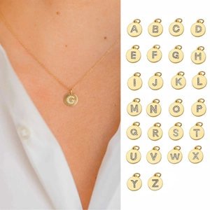 Detail view of gold 14K initial coin necklaces with cubic zirconia pavé letter pendants