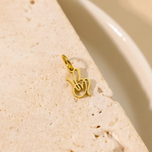Vue macro d'un pendentif doré poli au design abstrait posé sur une surface en pierre