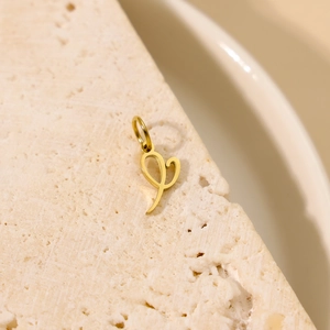 Vue macro d'un pendentif lettre en or poli sur pierre montrant les détails du métal