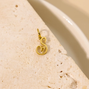 Gros plan détaillé d'un pendentif lettre S doré sur une surface en pierre texturée