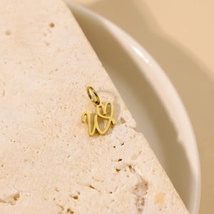 Pendentif lettre W dorée avec cœur sur une surface élégante en marbre poli