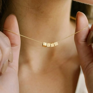 Close-up of LOVE engraved 14K gold plated cubic pendants on a delicate chain necklace