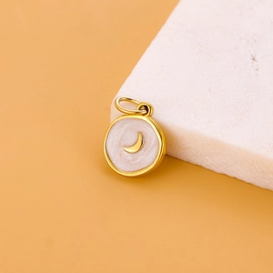 Detail of a round gold pendant with star and moon charms for DIY jewelry making