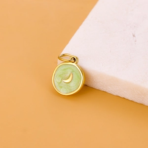 Detailed macro view of a golden moon pendant with green enamel for DIY jewelry making