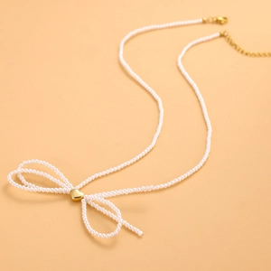 Detalle de collar de perlas con colgante de corazón dorado y diseño de lazo elegante