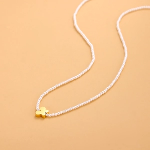 Primer plano de collar de perlas con un colgante de mariposa dorada de diseño elegante