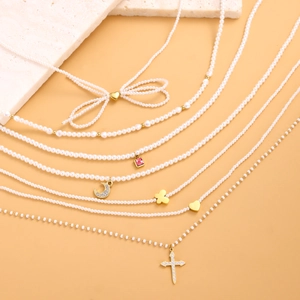 Collares de perlas de lujo francés con varios colgantes dorados sobre fondo amarillo