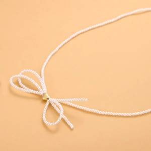 Collar de perlas de estilo francés con corazón dorado y lazo sobre fondo naranja