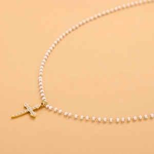 Elegante collar de cruz dorada con pavé de circonitas y cadena de perlas blancas fitte