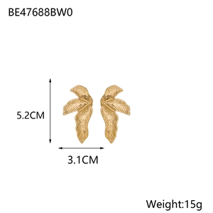 Dettaglio macro di orecchini a foglia oro opaco con venature sottili e dimensioni