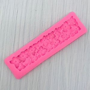 Macro view of pink silicone mold featuring intricate floral leaf patterns for cake decorating