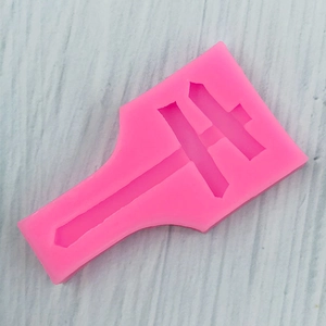 Detail showing bright pink sword-shaped silicone mold for DIY crafts on wood background