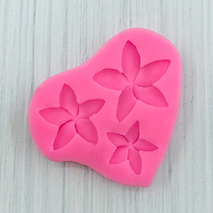 Macro detail of heart-shaped pink silicone mold with three flower patterns for DIY baking