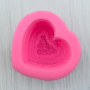 Detail view of pink silicone heart mold featuring intricate rose bouquet patterns for baking