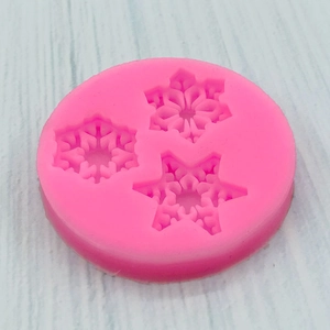 Pink silicone mold featuring three distinct snowflake patterns for DIY crafts and baking