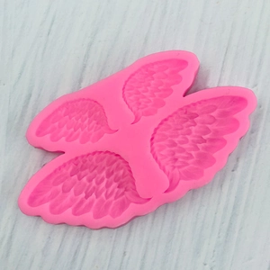 Détail macro du moule en silicone rose avec quatre tailles d'ailes d'ange texturées