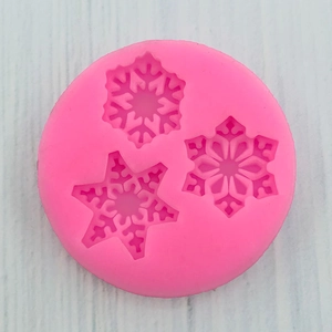 Detailed top view of pink silicone mold with three unique snowflake patterns for baking