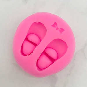 Pink silicone mold with baby shoes and bow designs for fondant cake or soap crafting