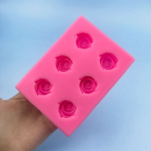 Pink silicone mold featuring six rose flower cavities for chocolate and baking crafts