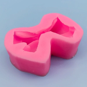 Pink 3D bow-shaped silicone mold for DIY chocolate and cake decorating on blue backdrop