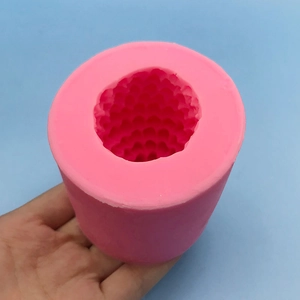 Handheld view of a pink cylindrical 3D pinecone silicone mold for cake and candle making