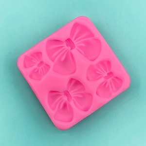 Dettaglio dello stampo in silicone rosa con quattro diverse forme di fiocco decorativo