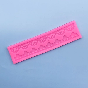 Close-up of pink silicone fondant mold with floral lace and leaf relief patterns