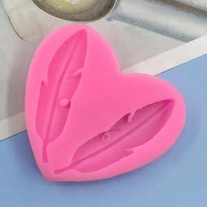 Close-up of pink heart-shaped silicone mold featuring detailed double feather patterns