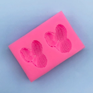 Detailed macro view of pink silicone mold featuring two realistic peanut shapes for baking
