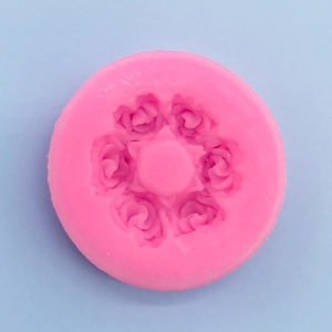 Macro view of a pink circular silicone mold featuring six detailed rose flower designs