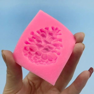 Handheld pink silicone mold featuring a detailed pinecone texture for cake decoration