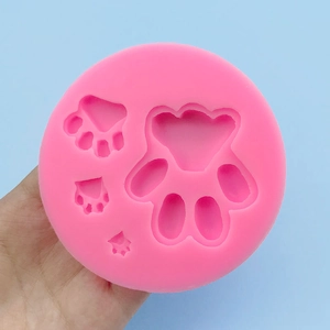 Pink silicone dog paw mold for DIY baking and chocolate crafts, held in hand for scale