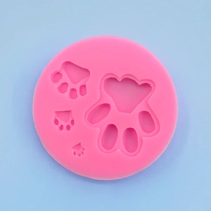 Detailed view of pink round silicone mold featuring four various sized paw print cavities