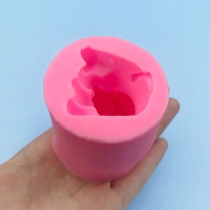 Hand holding a 3D pink silicone lion mold for making mousse cake or chocolate decor