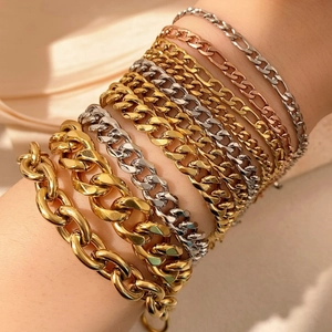 Stacked silver, gold, and rose gold stainless steel Cuban and Figaro chains on a wrist