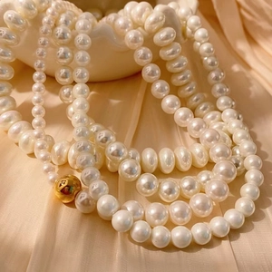 Collier élégant en perles crème multicouche avec fermoir doré sur fond de soie
