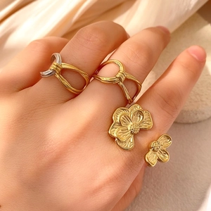 Dreiteiliges Set aus klobigen Gold- und Silberknotenringen und Blumenring am Modell