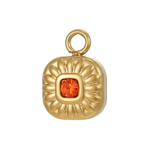 Macro detail of a gold sunburst square pendant with an orange gemstone inlay