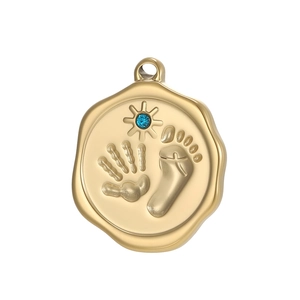 Detail of a gold medallion pendant with embossed handprints, footprints and blue zircon