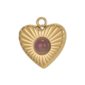Detail of heart pendant with pink gemstone and sunburst texture in gold plating