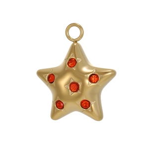 Détail macro du pendentif étoile dorée avec cristaux rouges et anneau de suspension